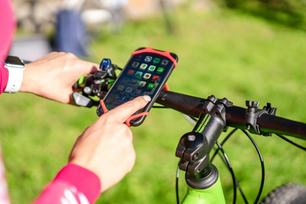 Close-up of a cyclist using a smartphone mounted on a bicycle handlebar for navigation outdoors.