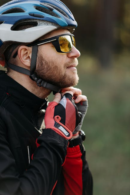 Side profile of a cyclist outdoors fastening his helmet with protective gear.