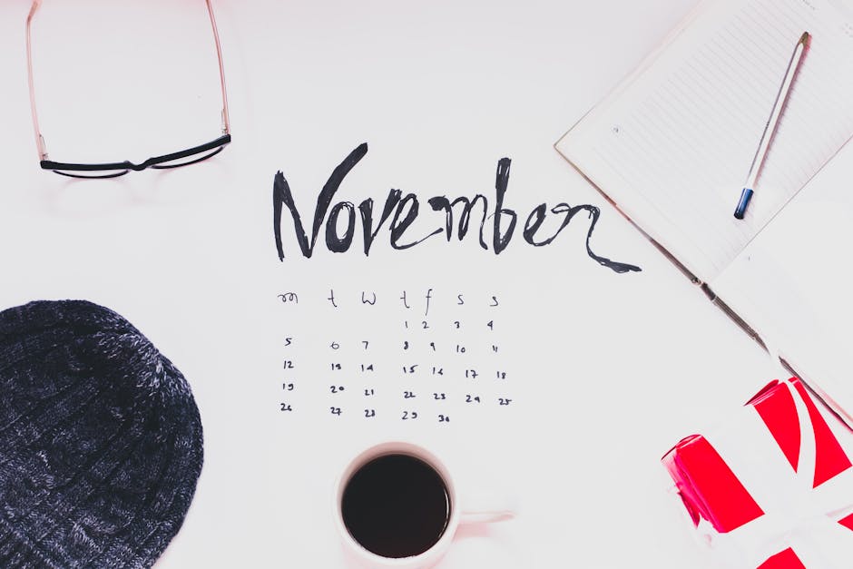 Flat lay of a November calendar with cozy autumn accessories, warm sweater, and hot coffee.