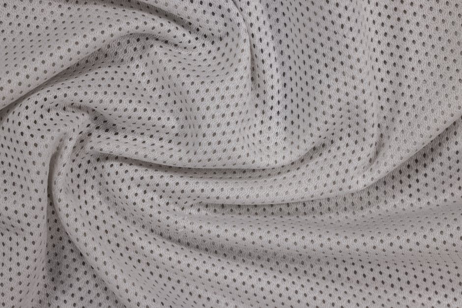 Close-up of textured white mesh fabric with a swirling pattern, highlighting its perforated design.