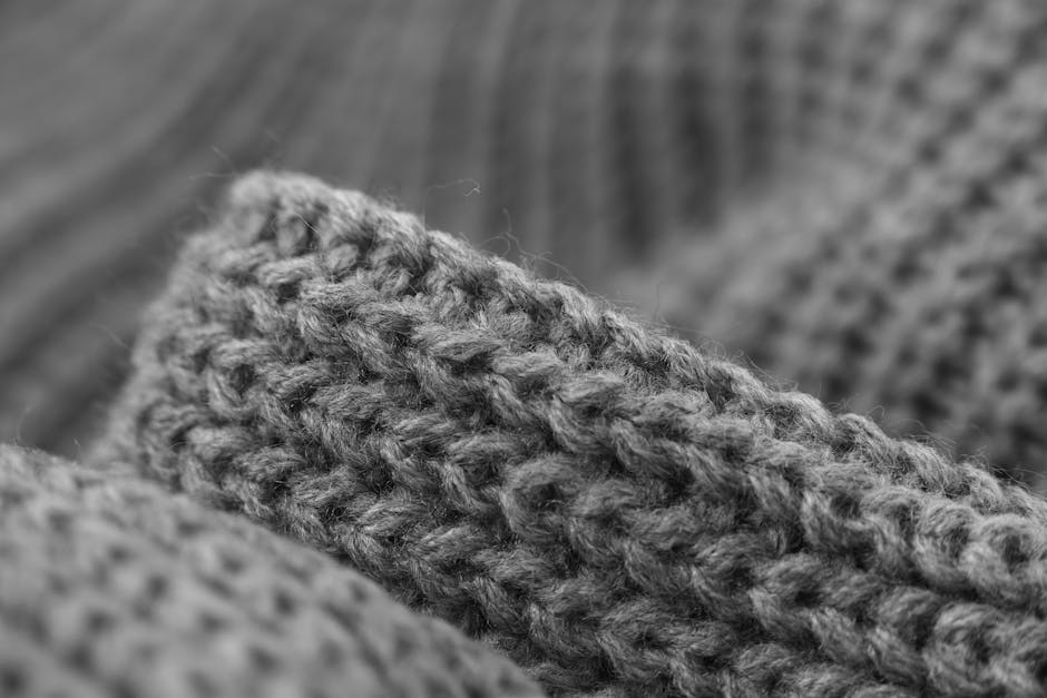 Macro black and white photo showcasing the intricate texture of grey knitted wool fabric.