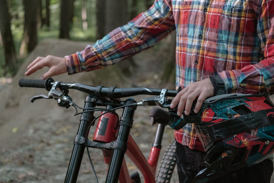 A mountain biker stands with their bike and gear in a forest setting, ready for outdoor adventure.