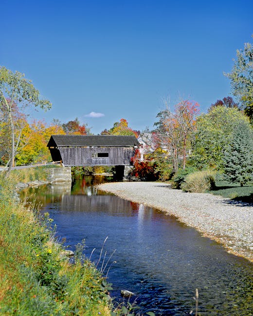 Picturesque autumn view of a covered bridge over a stream in Warren, Vermont.