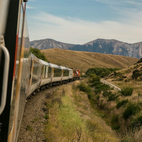 Scenic train traveling through the rolling hills of the American South under a blue sky.