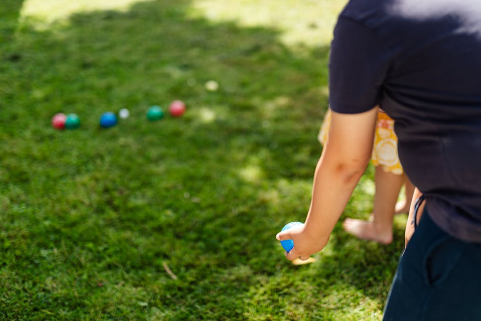 Classic bocce ball game setup being played by friends and family in a sunny backyard.