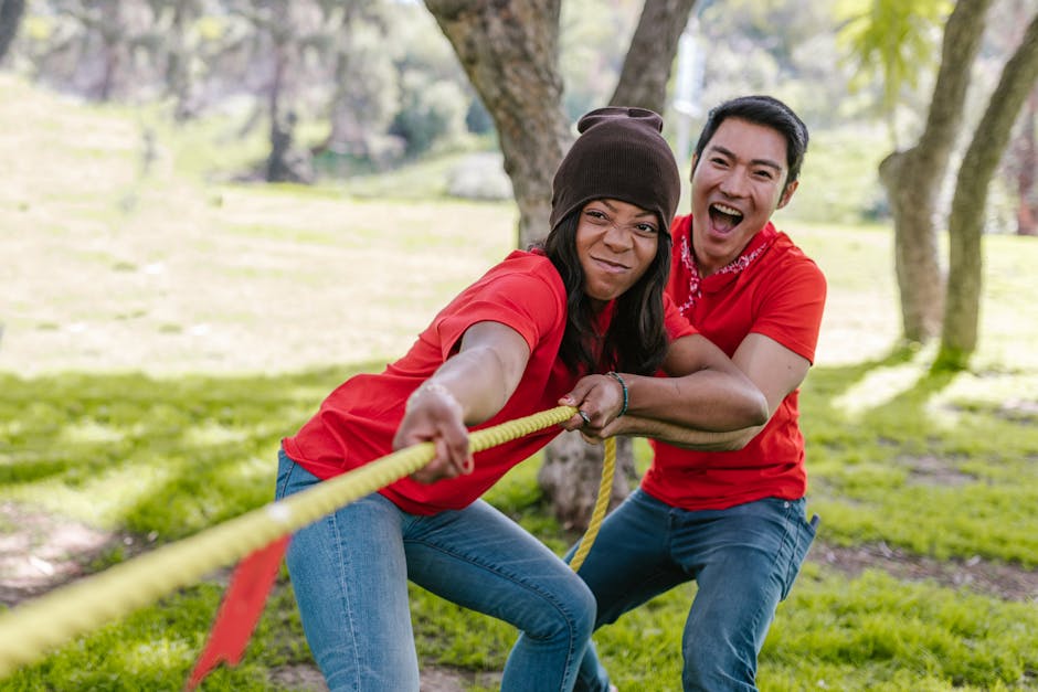 Team Strategy Challenges: Group of adults enjoying a tug of war during a team building exercise in a backyard.