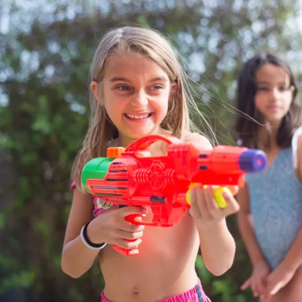Young child holding a colorful water gun, enjoying outdoor play on a sunny day.