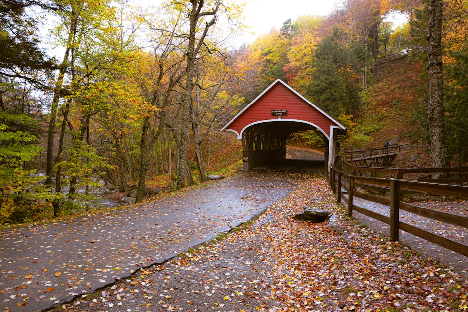 Beautiful autumn view of a covered bridge surrounded by fall foliage in Lincoln, New Hampshire.