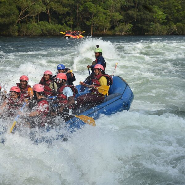 Group of adventurers white water rafting through a fast-moving river surrounded by rocky terrain and lush forest.