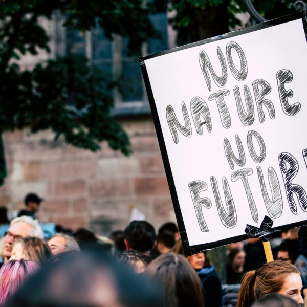 Large group of people rallying with a sign advocating for nature protection and climate action.